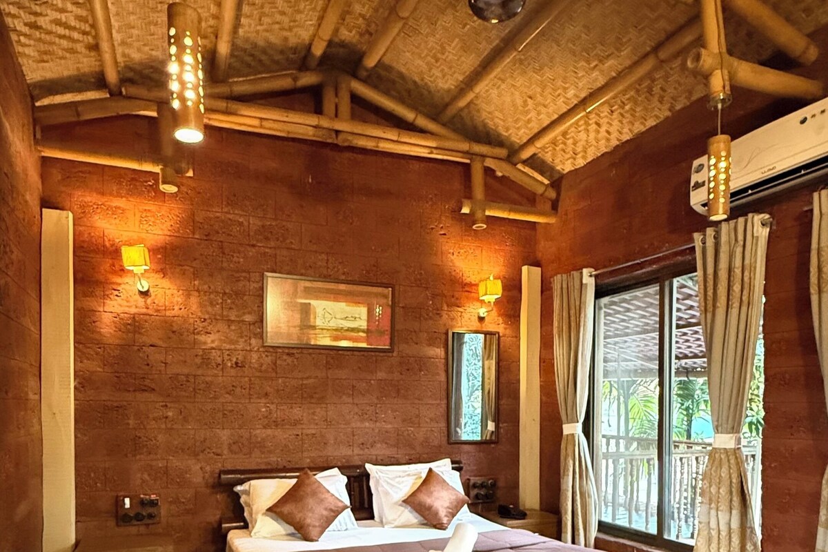 Een ruime slaapkamer met een groot bed, houten vloeren en een bamboe plafond.