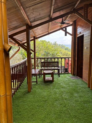 A covered outdoor area with a wooden deck, a bench, and a table.