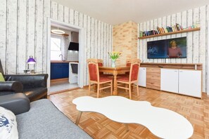 A living room with a dining table, red chairs, a sofa, a TV, and a bookshelf. - Holiday apartment "Seestern" (Esens-Bensersiel)