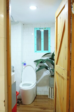 A small bathroom with a toilet, a window, and a potted plant. - Q homestay Vintage - tại chợ Bến Thành District 1 (Thành phố Hồ Chí Minh)
