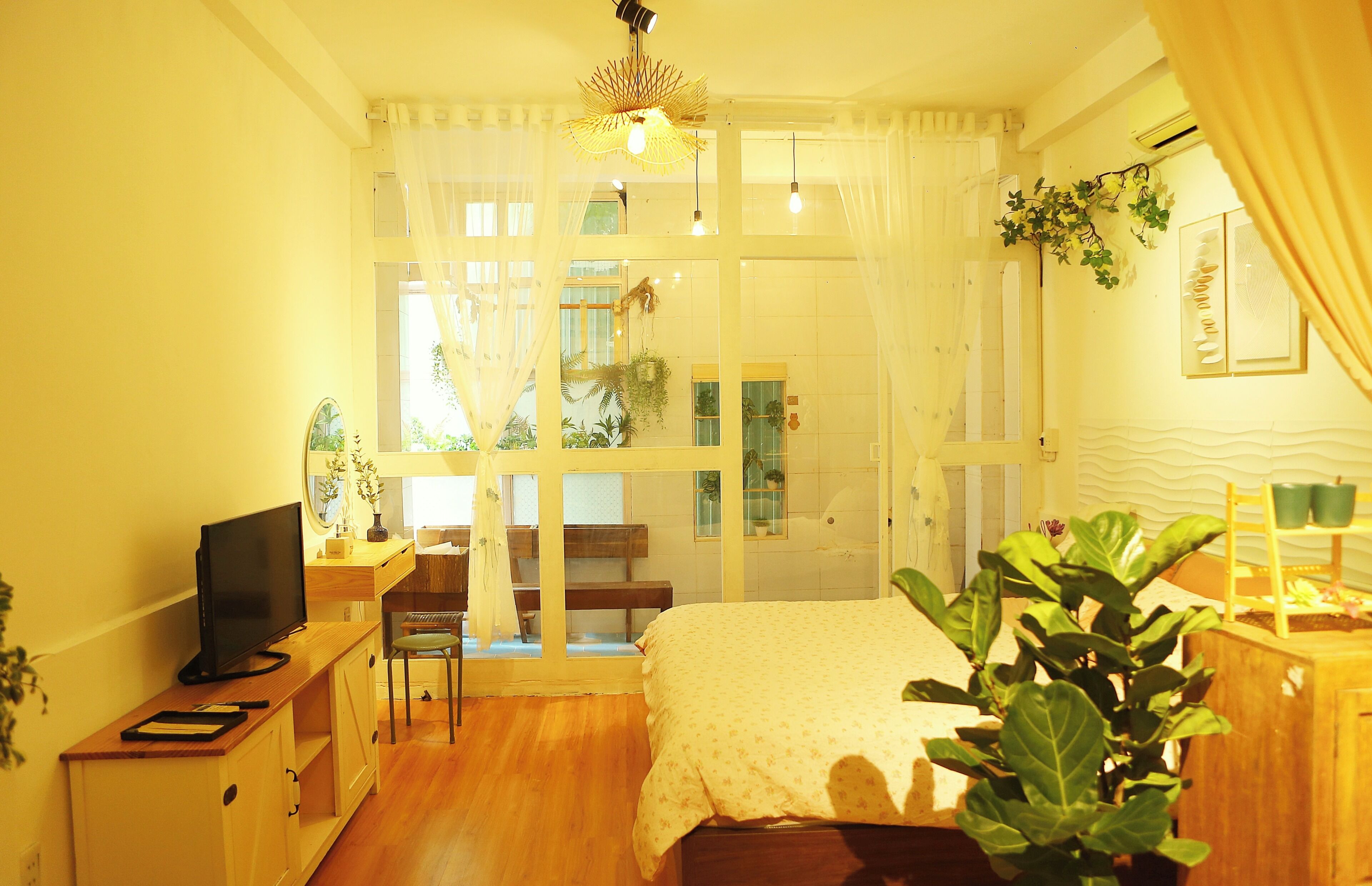 A room with a bed, a desk, a chair, a television, and a window with curtains.
