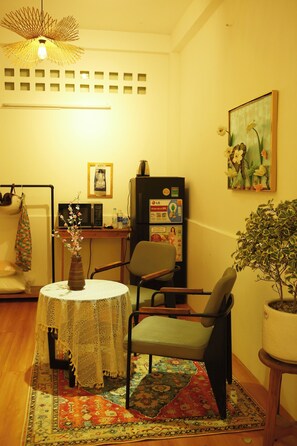 A living room with a round table, chairs, a potted plant, a painting, and a television. - Q homestay Vintage - tại chợ Bến Thành District 1 (Thành phố Hồ Chí Minh)