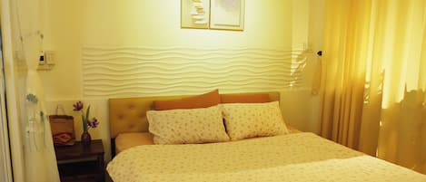 Une chambre à coucher avec un lit, une table de chevet, un vase de fleurs et des œuvres d’art murales.