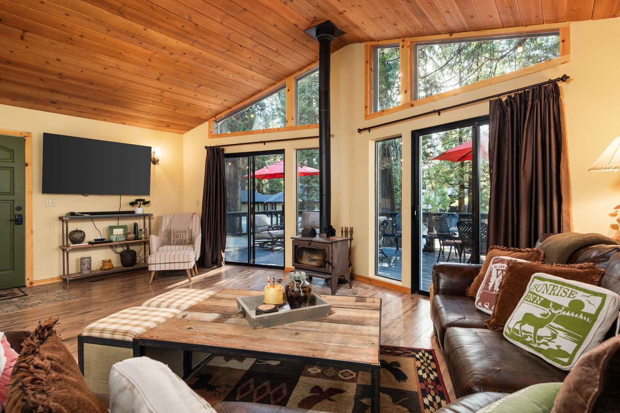 A cozy cabin interior with a fireplace, wooden floors, a sofa, and a television.