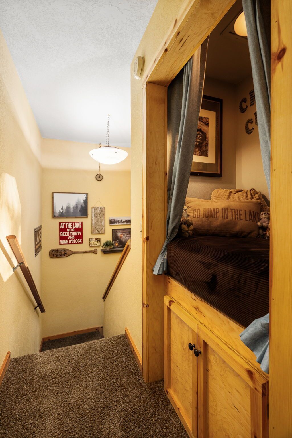 A cozy cabin-style room with a bunk bed, wooden walls, a ceiling fan, and a welcome sign.