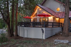 A two-story building with a deck, string lights, and outdoor seating. - Your cozy home away from home in Shaver Lake! (Shaver Lake)