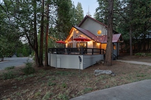 A cabin with a deck, surrounded by trees, and a satellite dish visible. - Your cozy home away from home in Shaver Lake! (Shaver Lake)