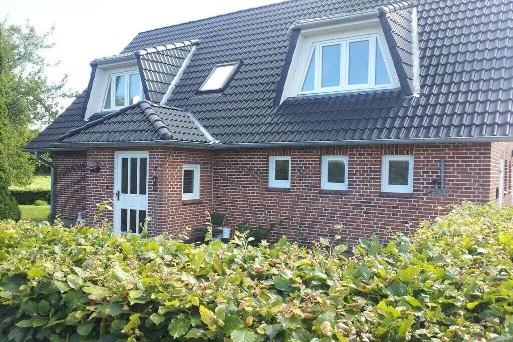 Une maison à deux étages, dotée d’un toit en pente, de lucarnes et d’une façade en briques.