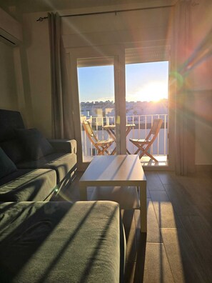 A living room with a sofa, a table, and two chairs. There is a balcony with a view of the city. - Vrbo Property (Vejer de la Frontera)