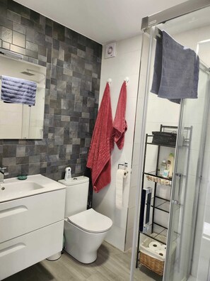 A modern bathroom with a shower, toilet, and sink. - Vrbo Property (Vejer de la Frontera)