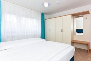 A bedroom with a bed, a wardrobe, and a mirror. - Holiday apartments "Im Watt" (Esens-Bensersiel)