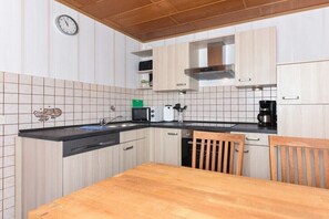 A kitchen with wooden cabinets, a black countertop, a sink, a microwave, a toaster, and a coffee maker. - Holiday apartments "Im Watt" (Esens-Bensersiel)