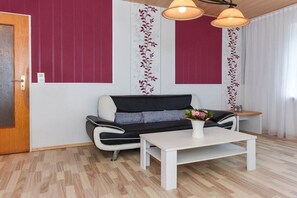 A modern living room with a sofa, a coffee table, and a decorative plant. - Holiday apartments "Im Watt" (Esens-Bensersiel)