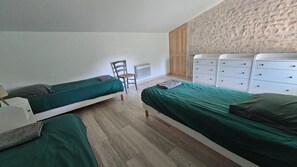 A room with two single beds, a chair, a white dresser, and a radiator. - Vrbo Property (Coulon)
