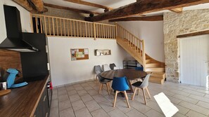 A dining area with a wooden table and chairs, a staircase, and a stone wall. - Vrbo Property (Coulon)