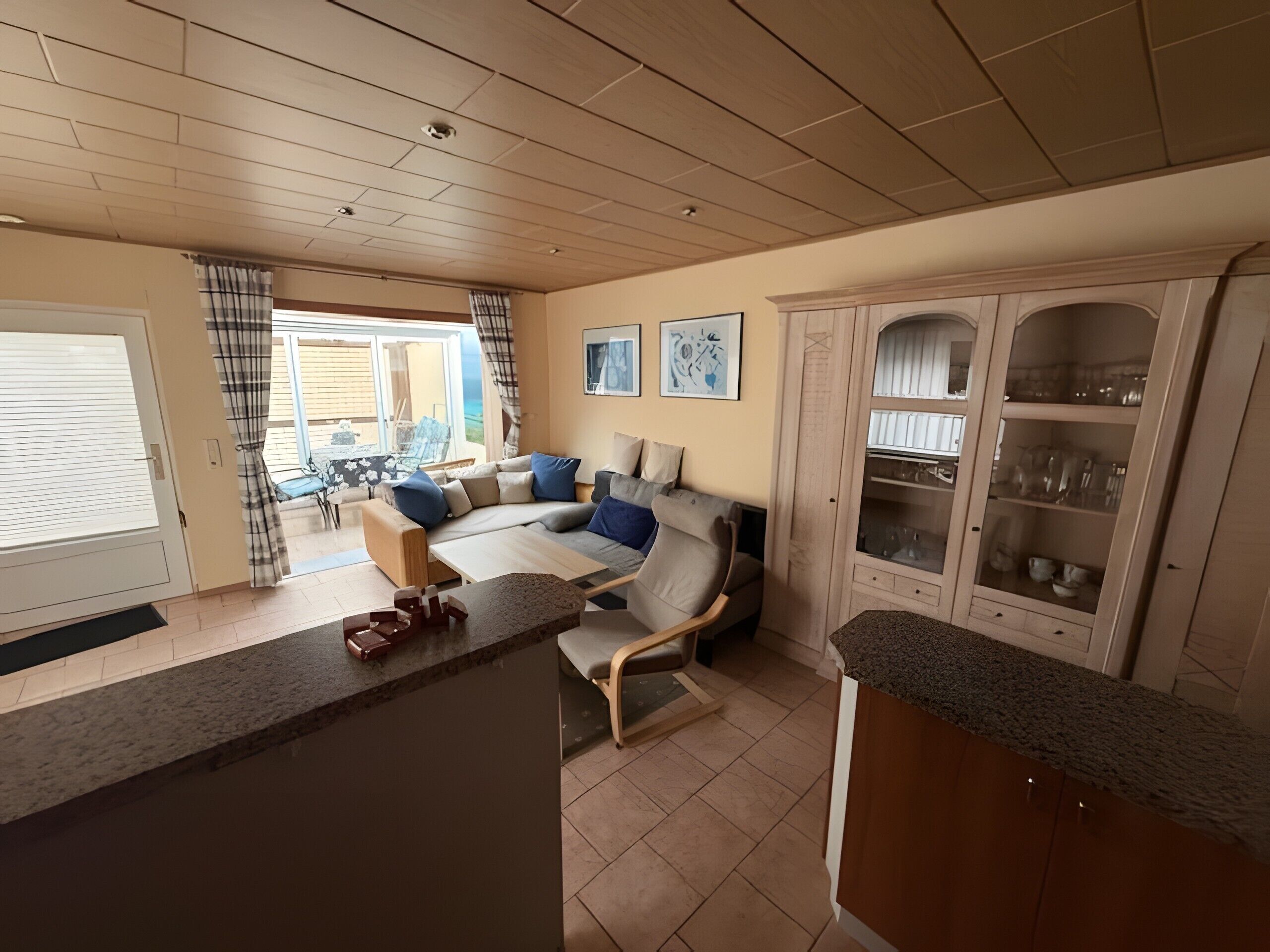 Amplia sala de estar con sofá, mesa de comedor y zona de cocina con armarios.