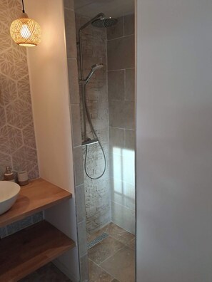 Een moderne badkamer met een douche, wastafel en een behang met een patroon.