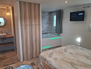 Een moderne badkamer met een houten garderobe, een inloopbad en een grote spiegel.