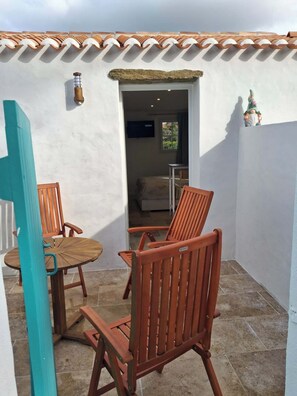 A patio with a table and chairs, a door, and a small shelf with a figurine.