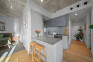 Une cuisine moderne avec un îlot central, des meubles de couleur grise et un plancher en bois.