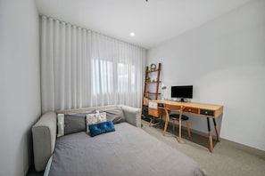 A bedroom with a bed, a desk, a chair, a TV, and a bookshelf. - Sunlit 2BD Apartment with Parking, Brunswick (Brunswick)