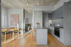 Una cocina moderna con armarios grises, una isla central y un comedor con sillas de madera y una mesa.