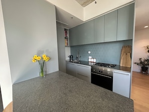 A modern kitchen with grey cabinets, a granite countertop, and a coffee machine. - Sunlit 2BD Apartment with Parking, Brunswick (Brunswick)
