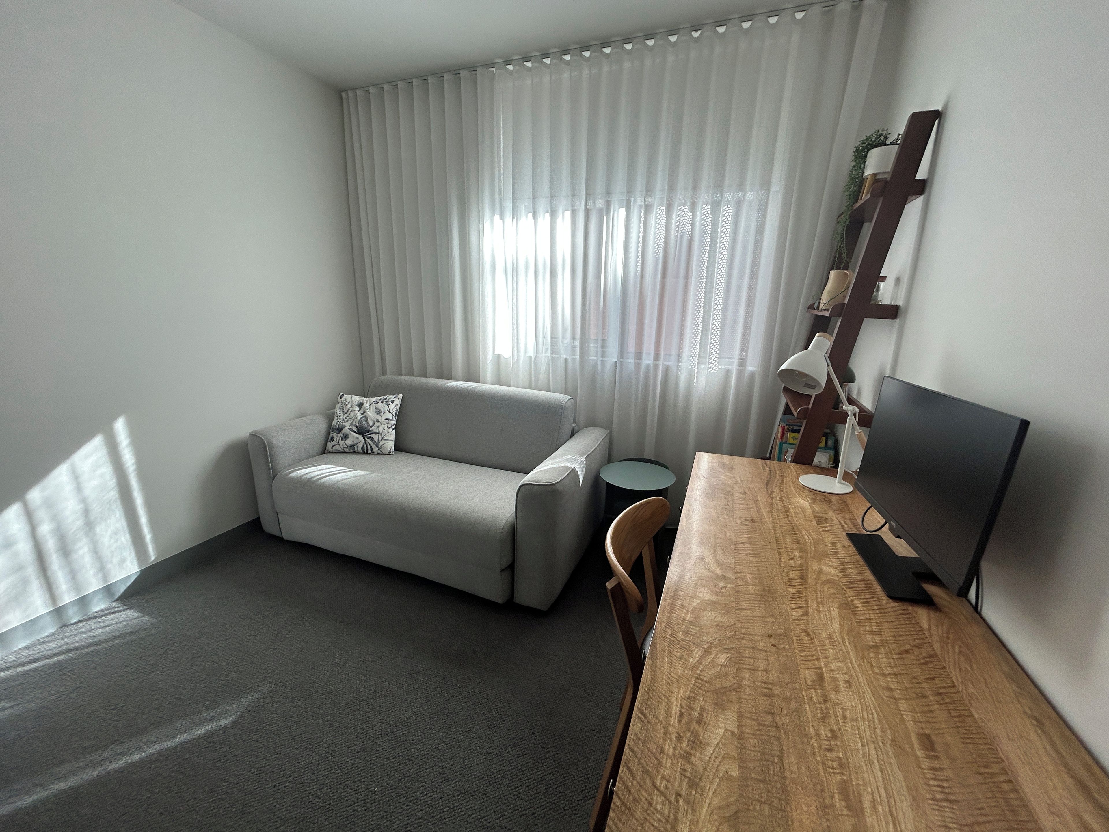 Una sala de estar con un sofá, una mesa de centro, un televisor y una estantería.
