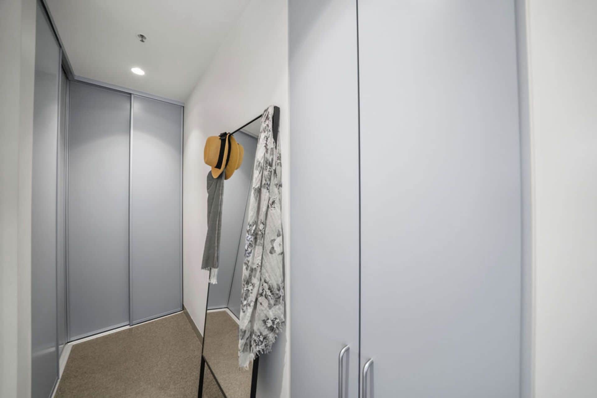 A hallway with a wardrobe, a hat, and a patterned cloth hanging on the wall.