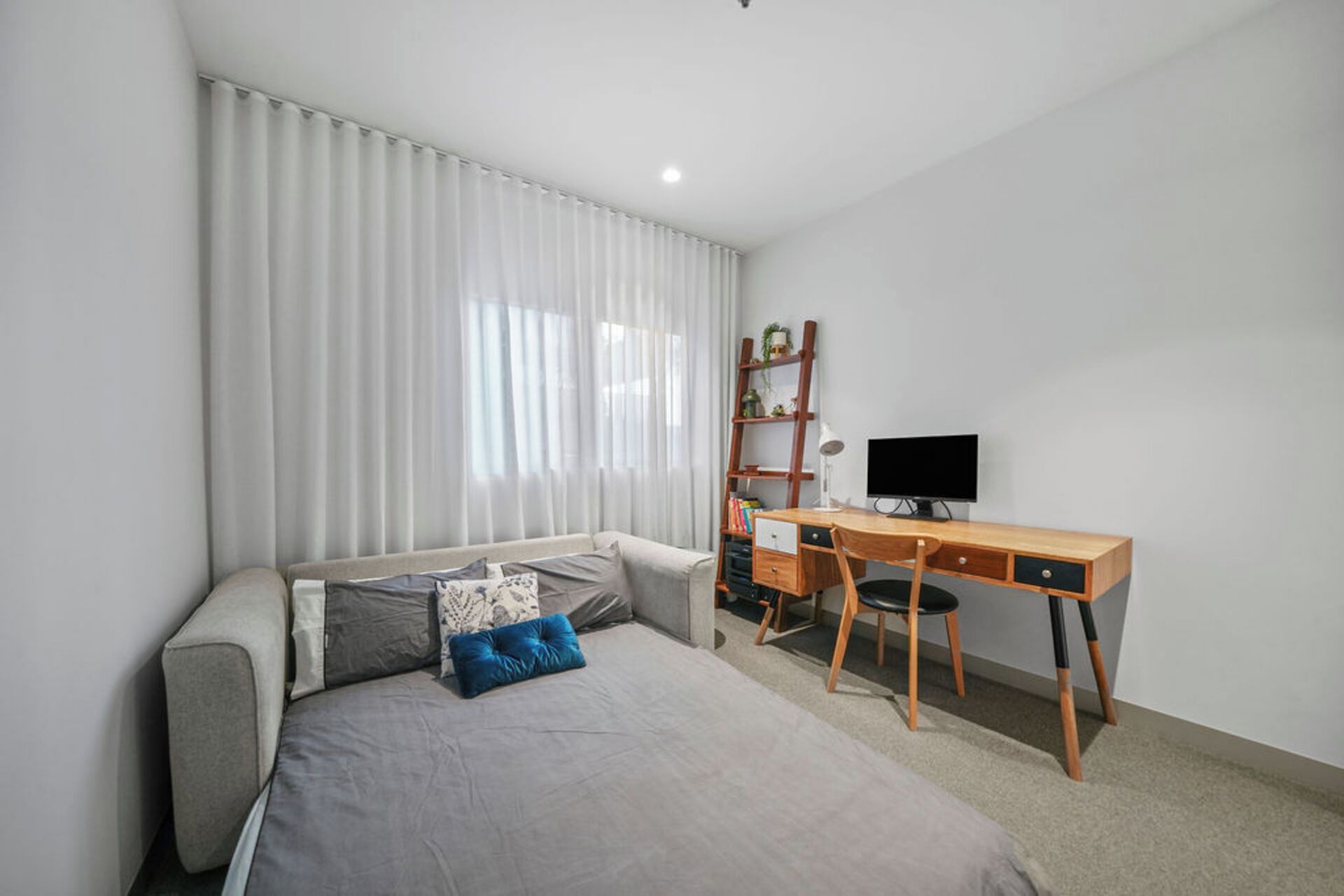 A bedroom with a bed, a desk, a chair, a TV, and a bookshelf.