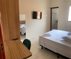 A hotel room with a bed, a TV mounted on the wall, and a shower area. - Hotel Paulista (São José do Rio Pardo)