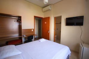A hotel room with a bed, a desk, a television, and a wardrobe. - Hotel Paulista (São José do Rio Pardo)