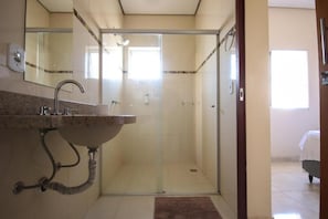 A bathroom with a glass-enclosed shower, a sink with a marble countertop, and a mirror above the sink. - Hotel Paulista (São José do Rio Pardo)