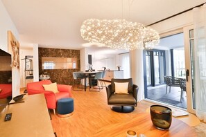 A modern living room with a dining area, a fireplace, and a large window. - Holiday apartment in Binz with swimming pool (Binz)