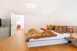 A bedroom with a bed, bedside table, lamp, and a view of a hallway. - Holiday apartment in Binz with swimming pool (Binz)