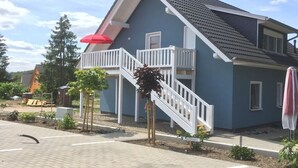 Een woongebouw met balkon, trap en een rode paraplu.