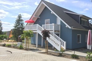 A residential building with a balcony, a staircase, and a red umbrella. - Holiday apartment with 2 bedrooms (Röbel\/Müritz)