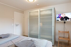 Ein Schlafzimmer mit einem Bett, einem Kleiderschrank, einem Fernseher und einem Sessel.