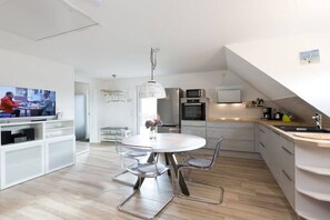 Eine moderne Küche mit Essbereich, einem Fernseher und einer Treppe.