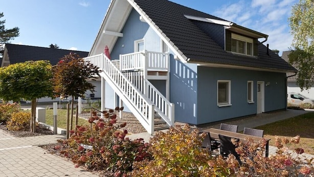 Een woonhuis met twee verdiepingen, een balkon, een trap en een terras met tuinmeubilair.