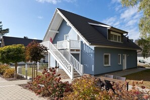 A two-story house with a balcony, a staircase, and a patio with outdoor furniture. - Holiday apartment with 2 bedrooms (Röbel\/Müritz)