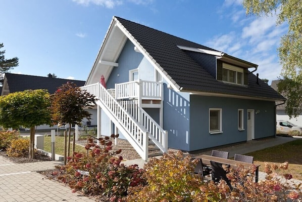 A two-story house with a balcony, a staircase, and a patio with outdoor furniture. - Holiday apartment with 2 bedrooms (Röbel\/Müritz)