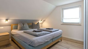 Een slaapkamer met een bed, nachtkastjes, een raam en wandlampen.
