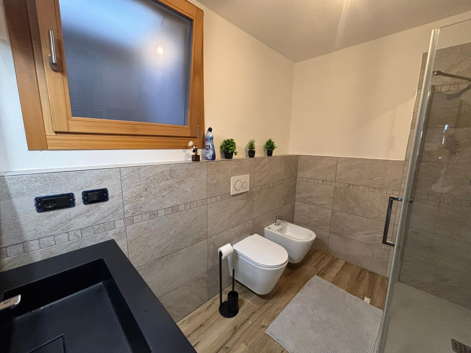 A modern bathroom with a shower, toilet, and bidet.