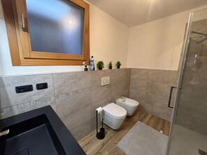 Et stilfuldt badeværelse med bruser, toilet og bidet.