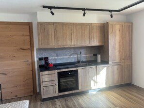 A kitchen with wooden cabinets, a black countertop, a coffee maker, and a dishwasher. - Villa Emma (Costalissoio)