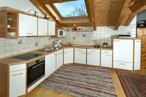 Eine Küche mit Dachfenster, weißen Schränken, einem Herd und einer Mikrowelle.