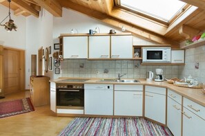 A modern kitchen with white cabinets, a built-in microwave, and a dishwasher. - Christine Penners 2 - "Kampenwand" (Aschau i. Chiemgau)