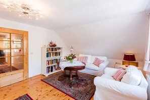 Una sala acogedora con un sofá blanco, una mesa de centro de madera y una estantería.