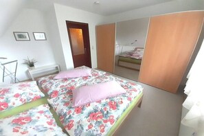 Een slaapkamer met twee bedden, een garderobe en een spiegel.